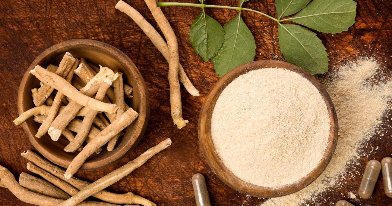 This is a picture of ashwagandha root next to a wooden bowl of ashwagandha root powder on a wooden table