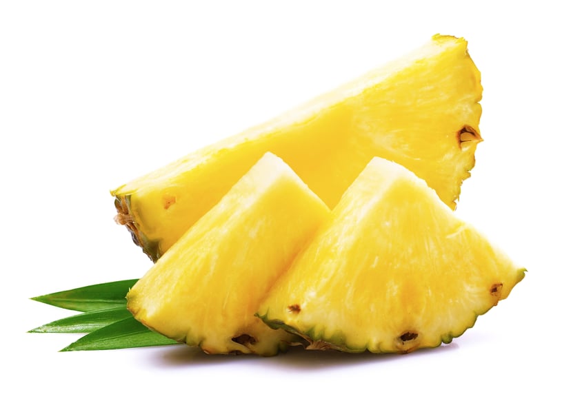 Image of pineapple quarters with green leaves in background.