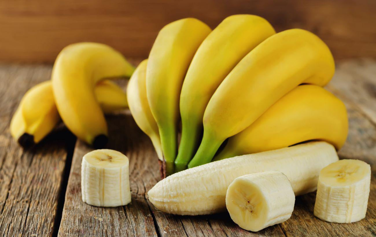 This is a picture of ripe bananas with some cut banana pieces on a wooden table