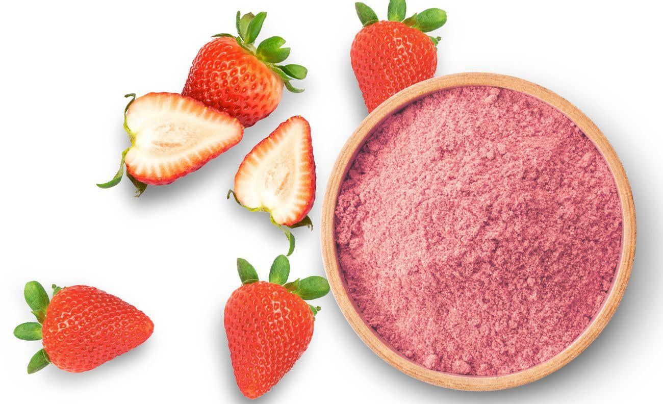 This is a picture of fresh strawberries and a wood bowl of strawberry powder on a white background