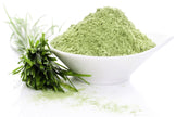 Barley Grass Powder in a pile on a white bowl with cut barley grass