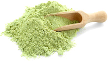 Barley Grass Powder with wooden spoon in a pile