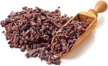 Image of Cacao Nibs with wooden serving scoop on white background.