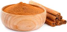 Image of Ceylon cinnamon powder in a wood bowl with cinnamon sticks next to it