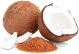Image of a pile of brown Coconut Palm Sugar next to fresh coconuts one of whom is cracked opened