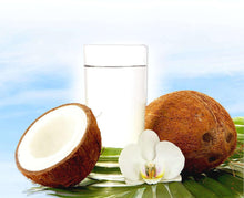 Photo of glass of Coconut Water next to one whole coconut and one half coconut and an orchid flower