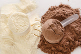 Image of white whey protein isolate next to dark brown cacao powder and 2 plastic scoops