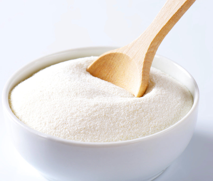 Image of Goat Milk Powder in a white bowl with a wooden spoon