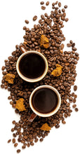 Image of coffee beans mixed with chunks of chaga and 2 coffee mugs full of coffee in the middle