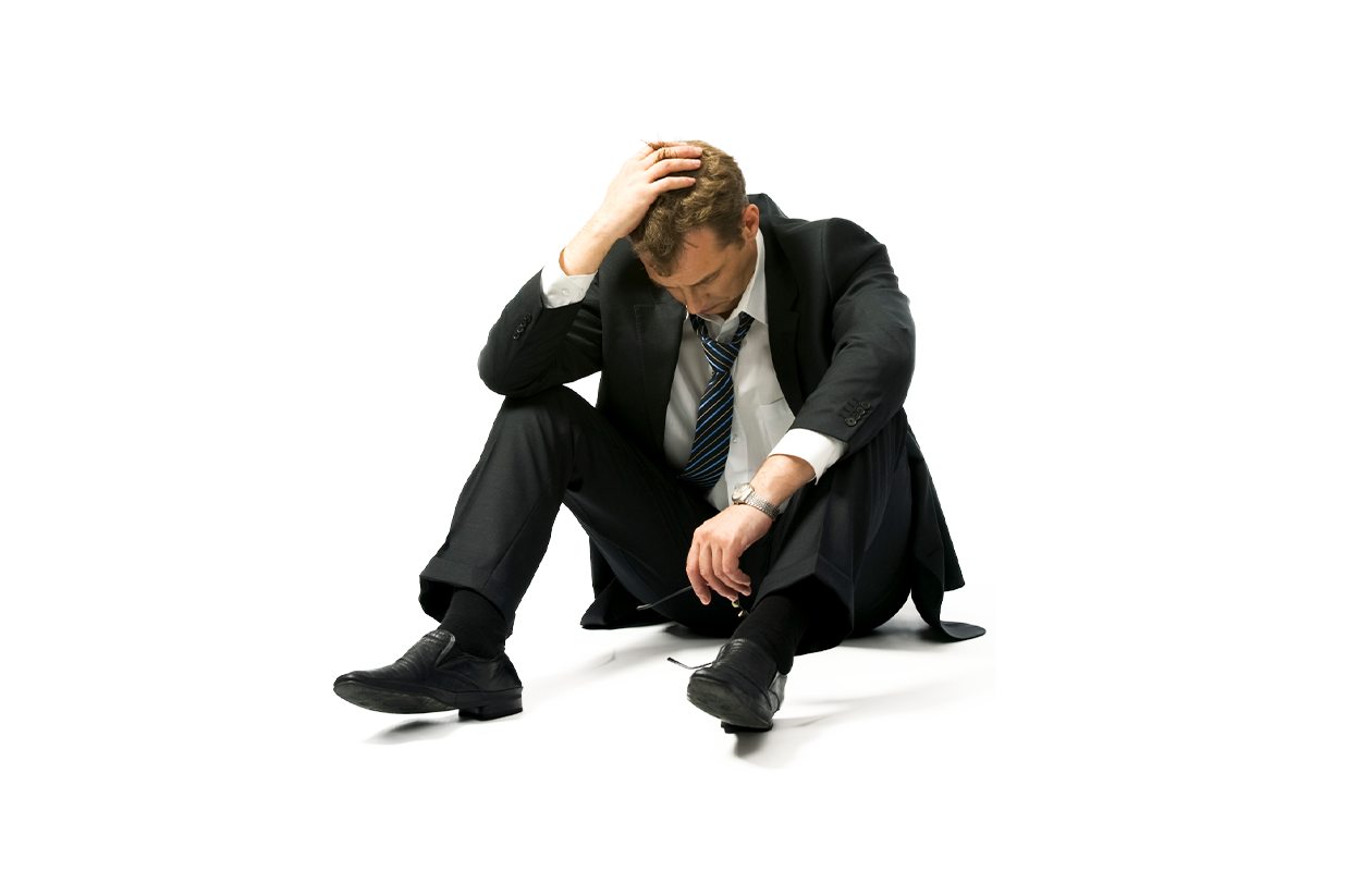 Photo of man dressed in suit sitting on ground with hand on head because of high stress and anxiety