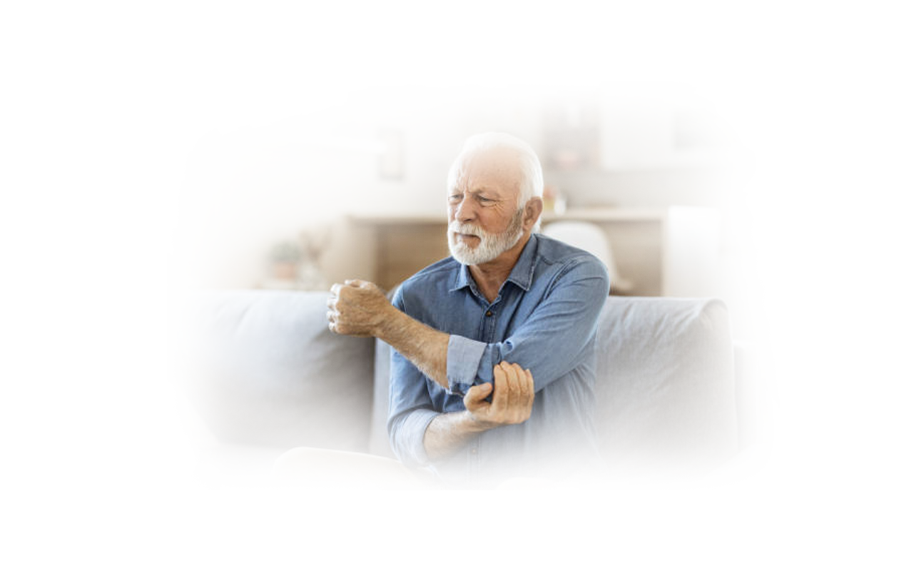 Image of man in agony sitting on couch holding elbow suffering symptoms of gout.