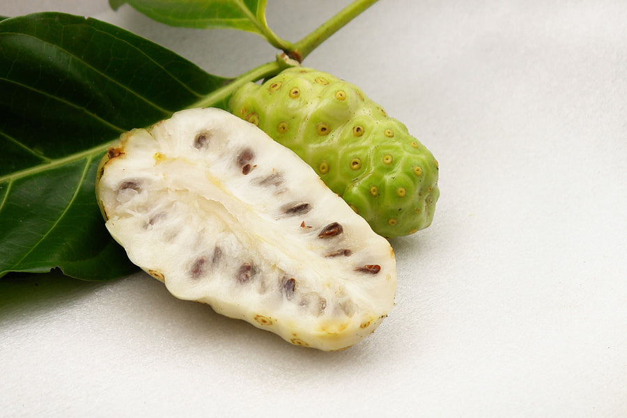 Image of fresh noni in it stem with one cut in half