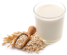Photo of glass of Oat Milk with wood spoon full of whole oats next to the glass