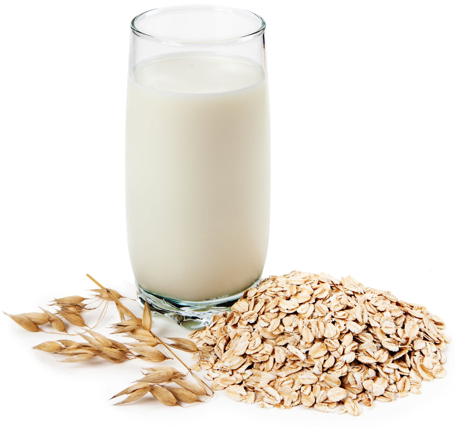 Image of a glass full of Oat milk and some oats next to it