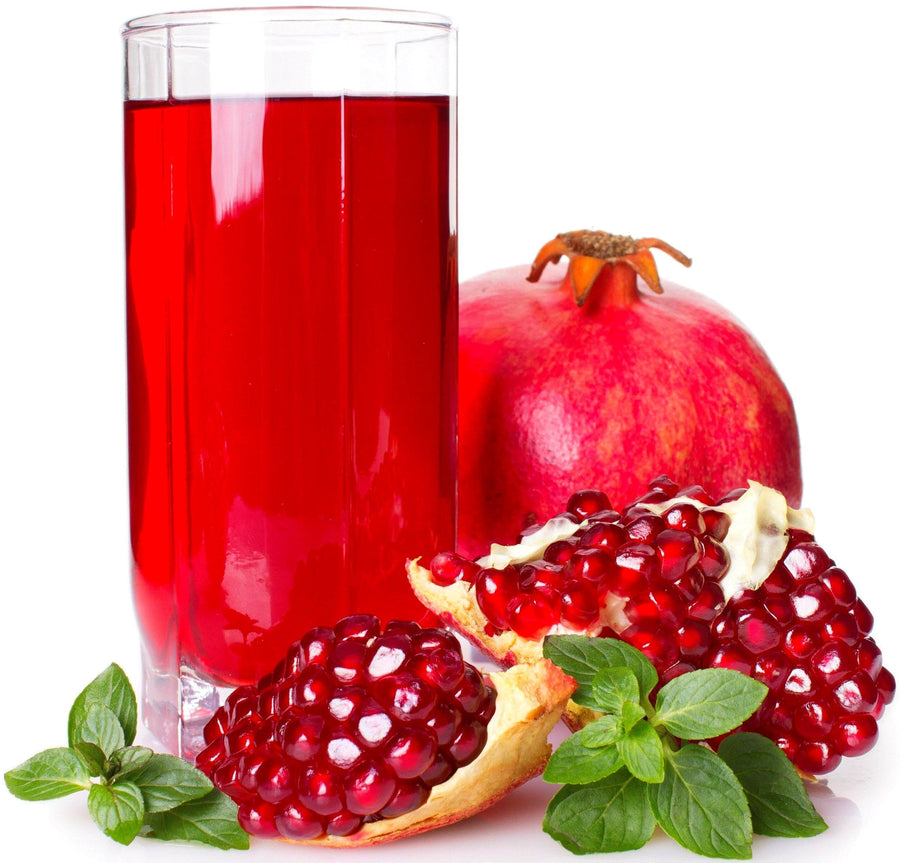 Image of a glass of red pomegranate juice surrounded by fresh pomegranate fruit