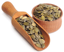 Image of green pumpkin seeds in a wooden scoop and bowl