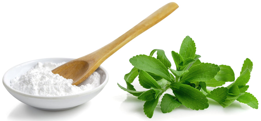 Small white bowl full of white Stevia Extract Powder (Debittered) and wood spoon with several green stevia plant leaves