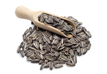 Image of whole Sunflower Seeds with wooden serving scoop on white background