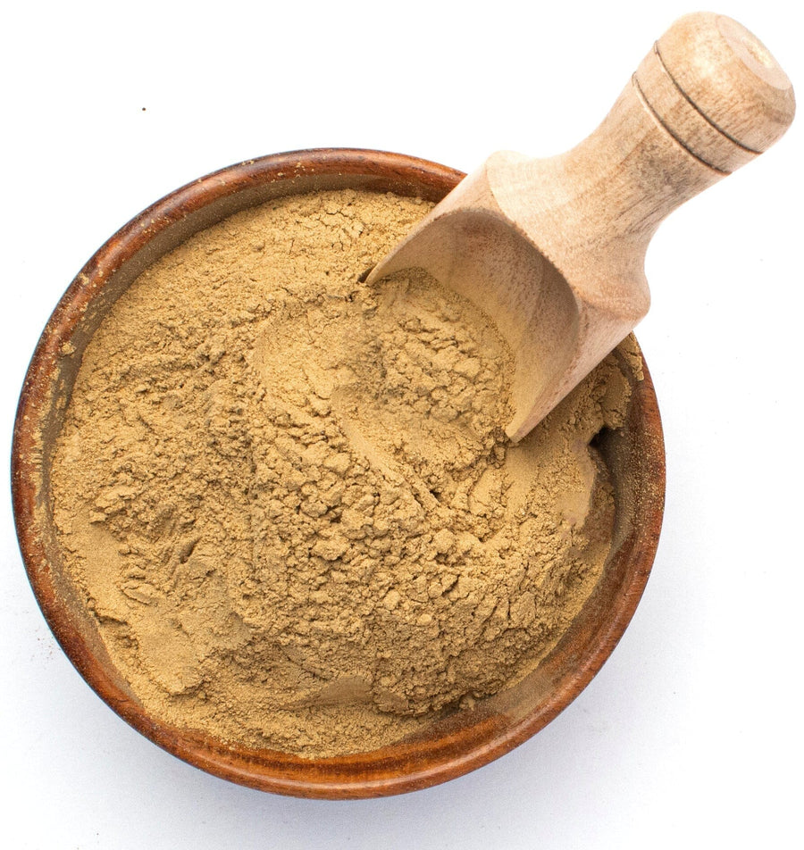 Over head image of Triphala (Trifala) Powder in wooden bowl with wooden serving scoop inserted in the powder.