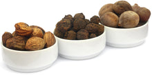 Closeup image of white bowls with actual whole raw fruits used in making Triphala, Amla, Harada, and Behada