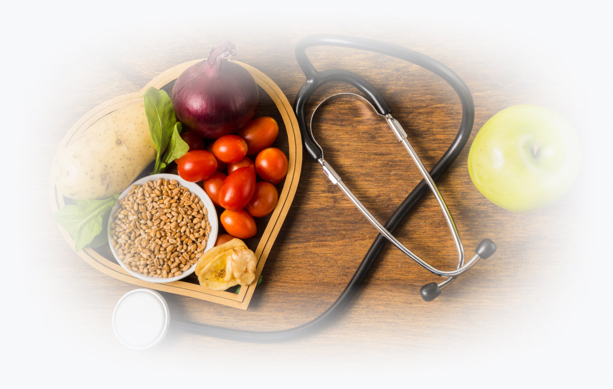 Overhead image of stethoscope with heart shaped container with potato, onion, and tomatoes inside of it.