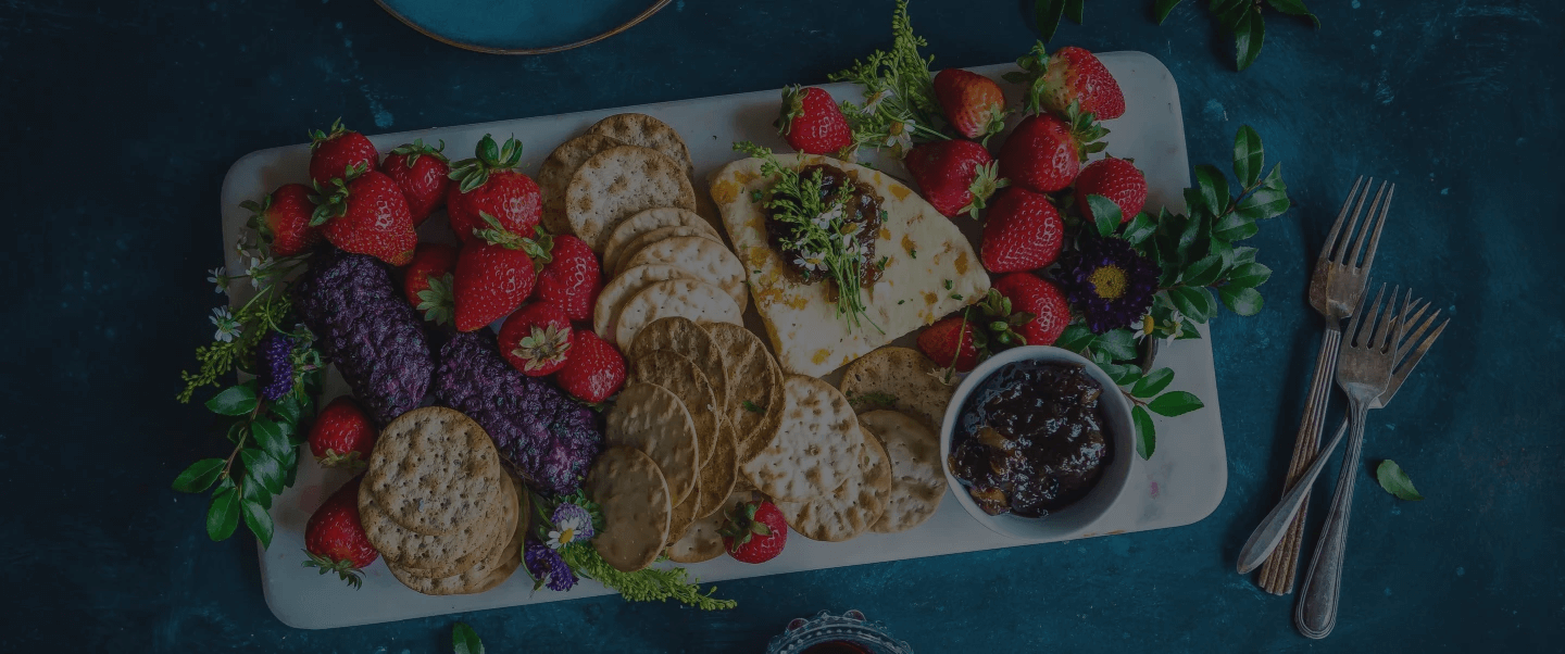Banner Image of rectangular platter with strawberries, assorted crackers, and cheese.